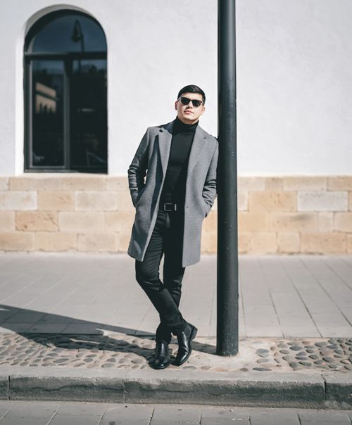 Free A fashionable man wearing sunglasses and a coat poses against a pole in Ciudad de Guatemala, Guatemala. Stock Photo