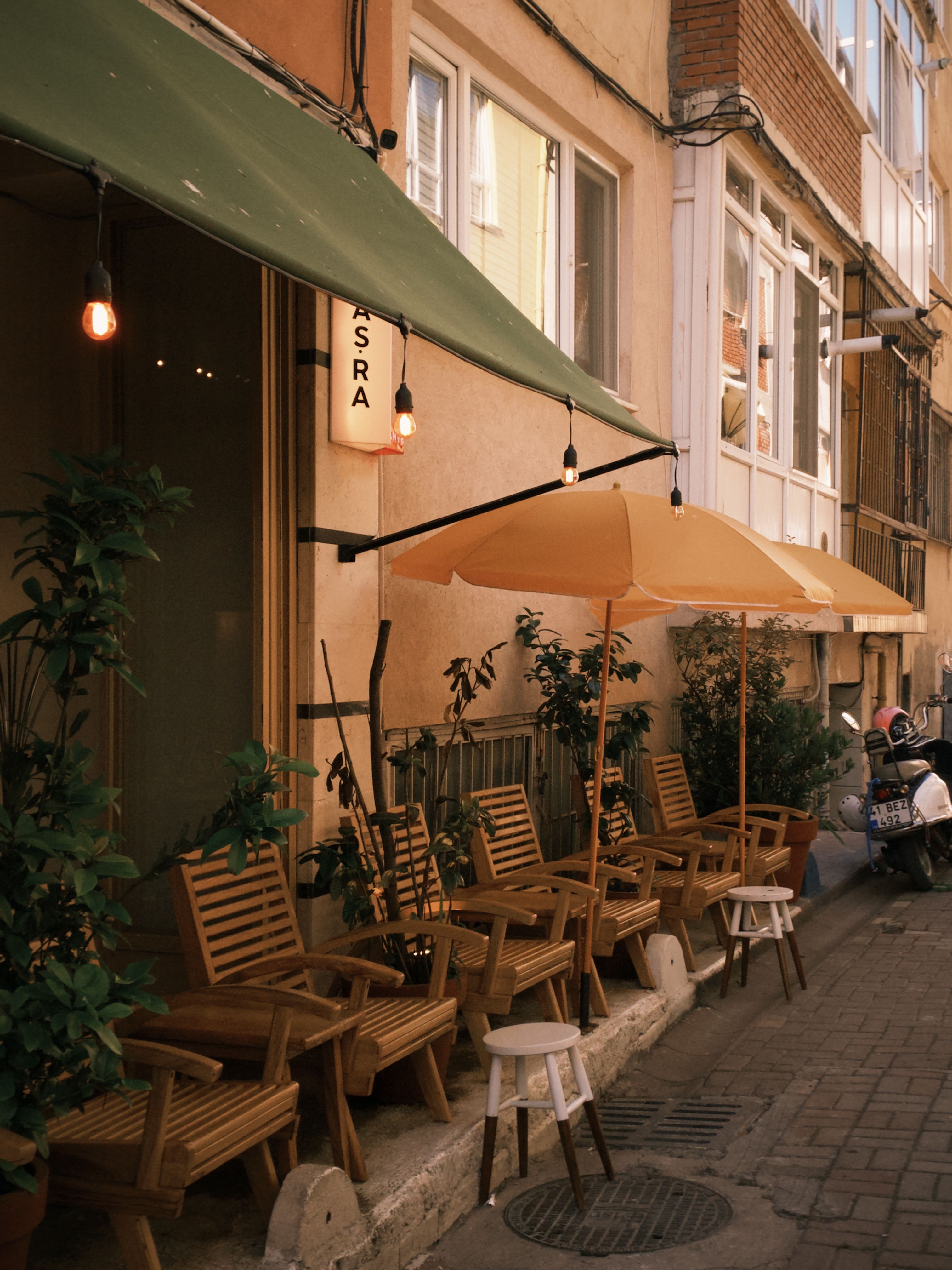 Charming outdoor cafe with wooden chairs and umbrellas on a cobblestone street, exuding an inviting atmosphere.