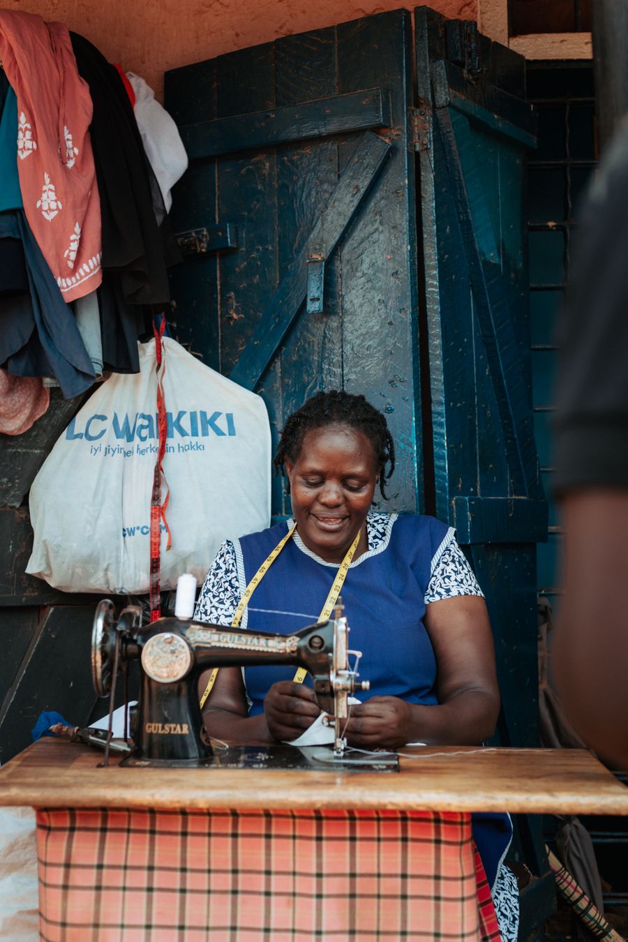 Zambian woman sewing clothes on a vintage sewing machine