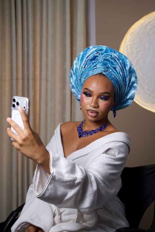 Free A stylish Nigerian woman wearing a blue gele and elegant jewelry takes a selfie indoors. Stock Photo