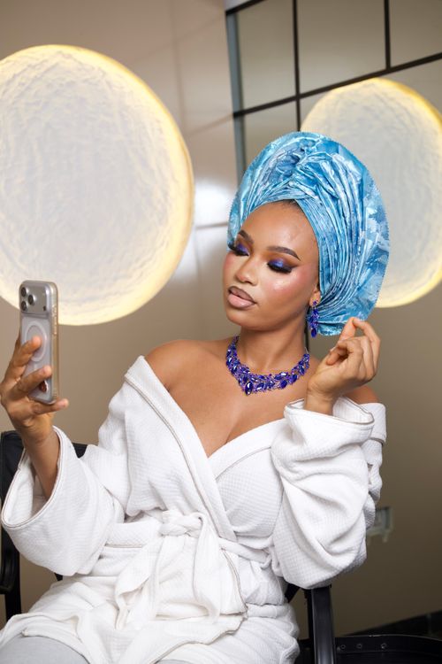 Free A stylish woman in a blue headwrap and jewelry takes a selfie indoors, showcasing Nigerian fashion. Stock Photo