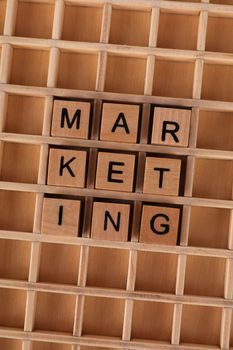 Wooden letter tiles arranged to spell 'marketing' on a wooden grid, depicting business strategy.
