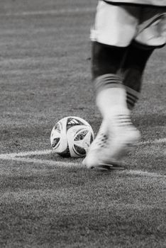 A soccer player prepares to kick a ball on the field. Captured in black and white for a classic look.