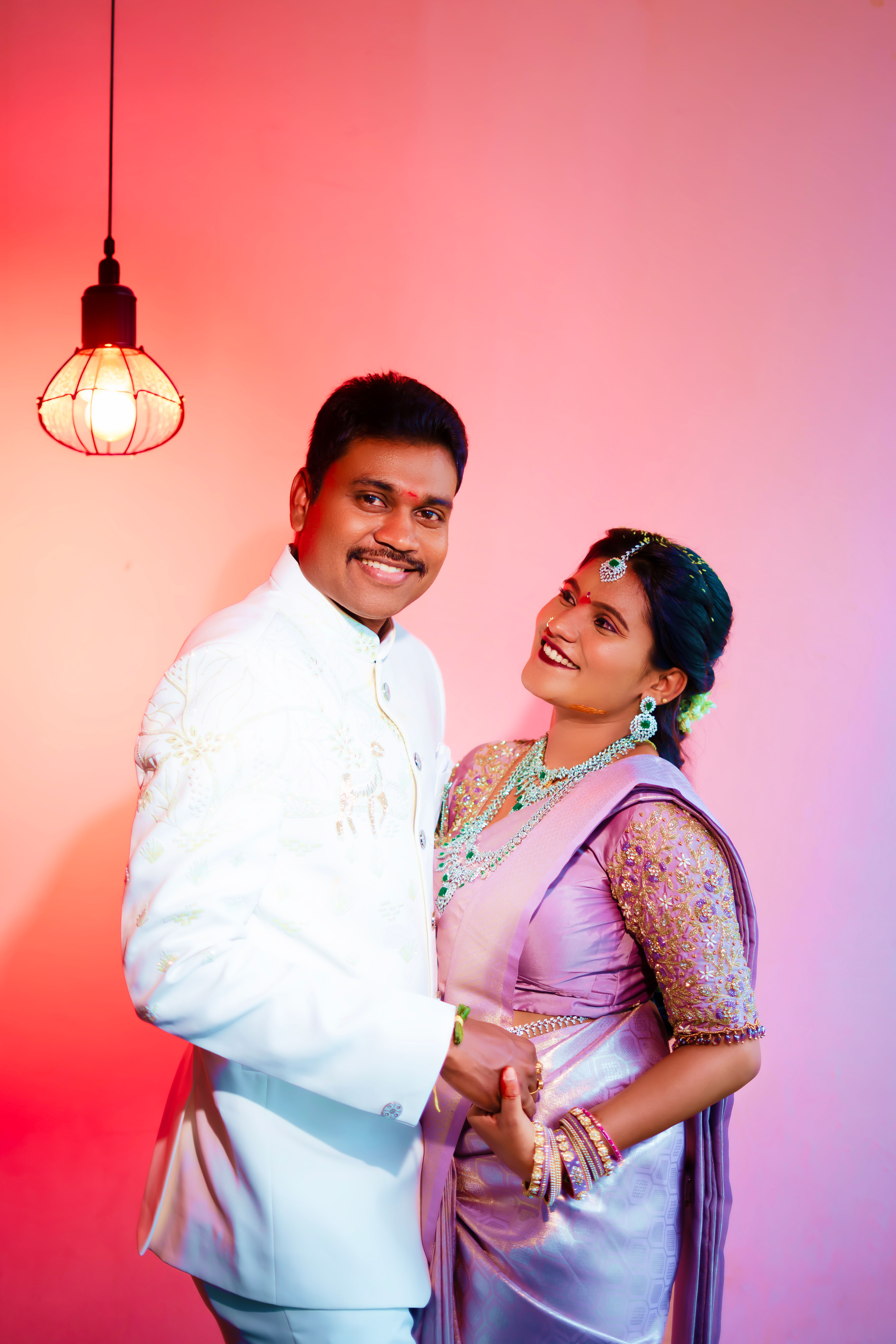 A happy South Indian couple poses in elegant attire under warm lighting, captured in Hyderabad.