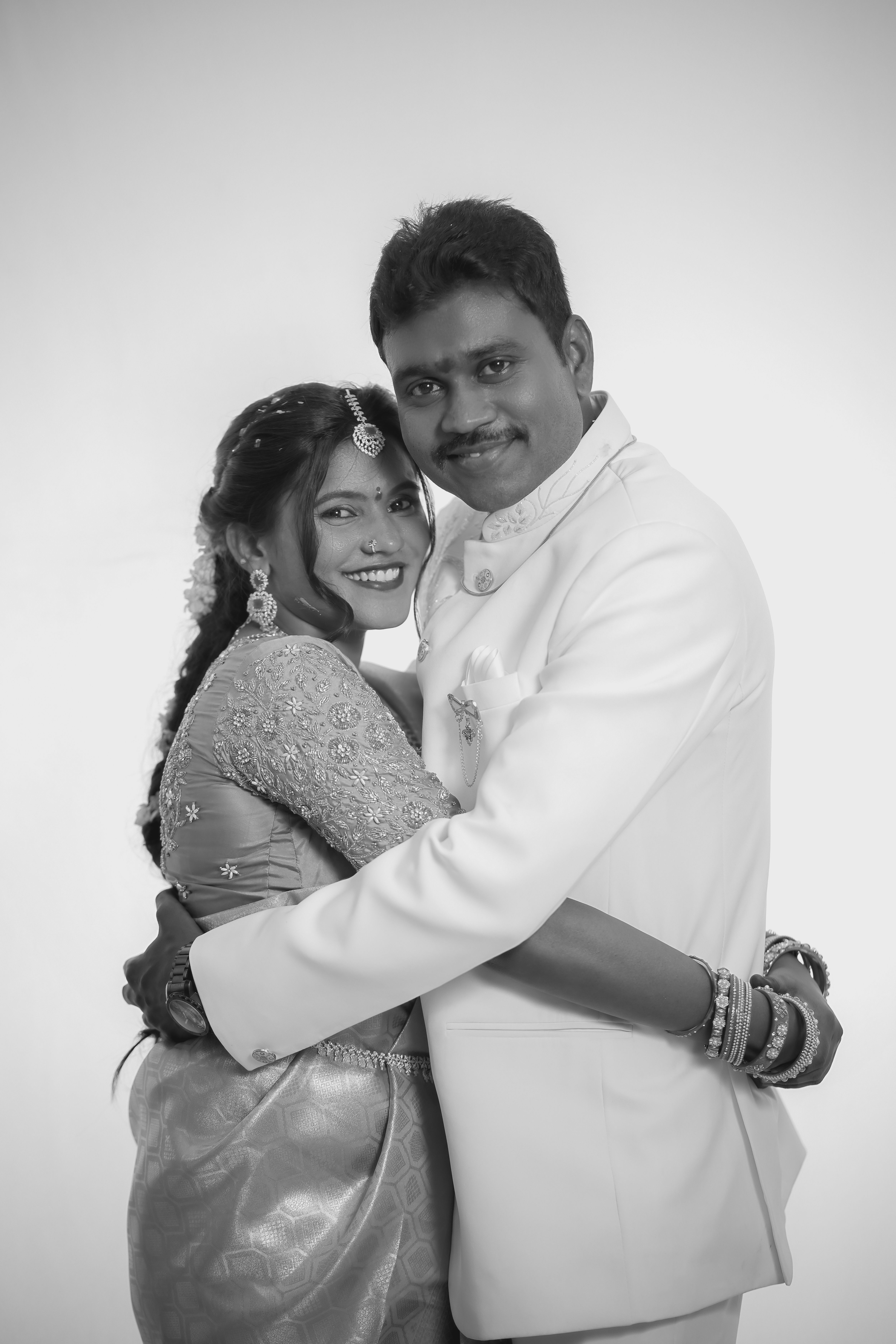 A romantic black and white portrait of a South Indian couple on their wedding day, embracing lovingly.
