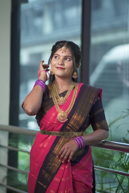 Free Portrait of a South Indian bride in a sari, adorned with traditional jewelry, smiling indoors. Stock Photo