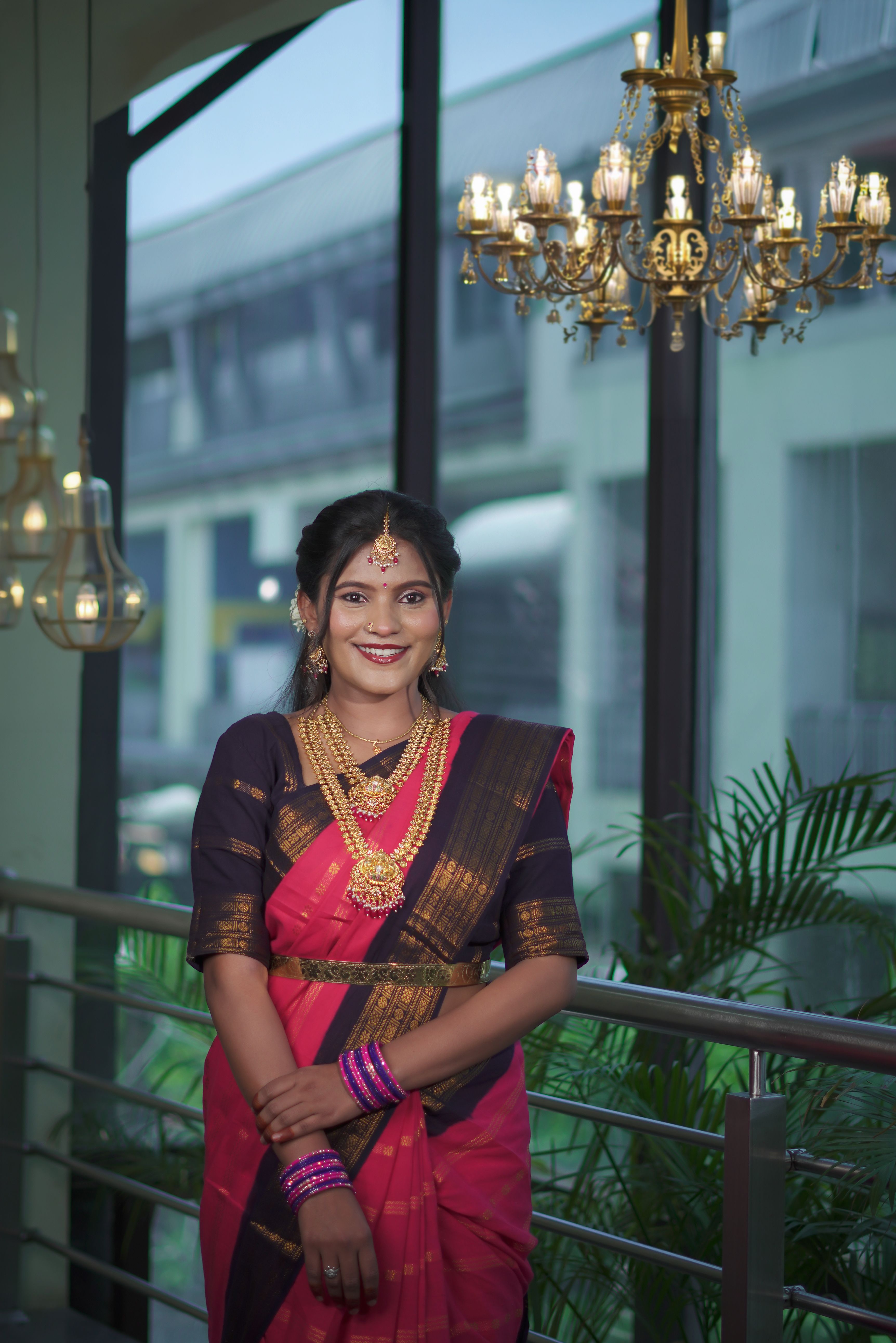 A South Indian woman in traditional saree and jewelry indoors, showcasing cultural elegance.