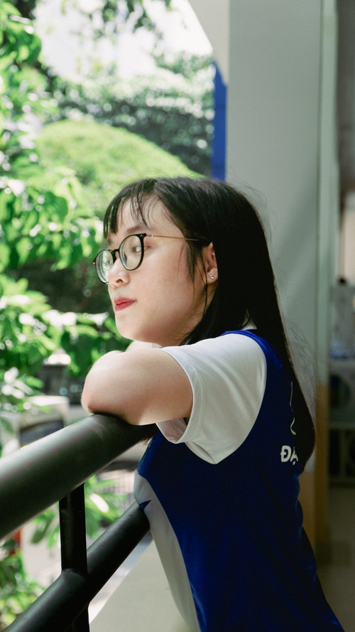 Free Young woman leaning on balcony railing, enjoying a peaceful nature view. Stock Photo