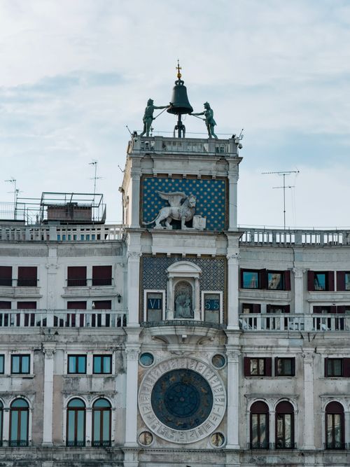 Free St Mark's Clock Tower in Venice featuring the iconic winged lion symbol against a blue sky. Stock Photo