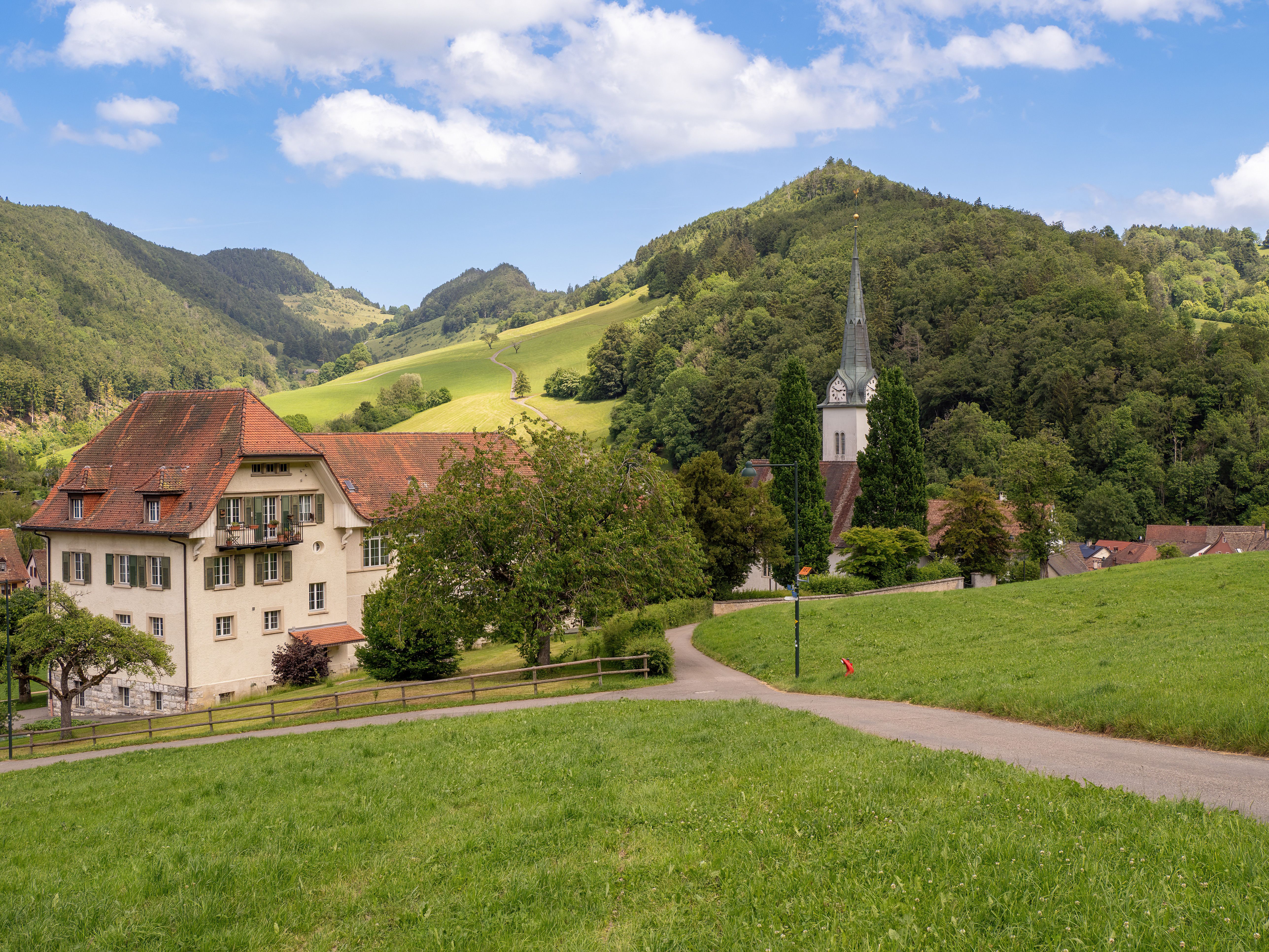 Charming Swiss village with traditional architecture, lush green hills, and a picturesque church.