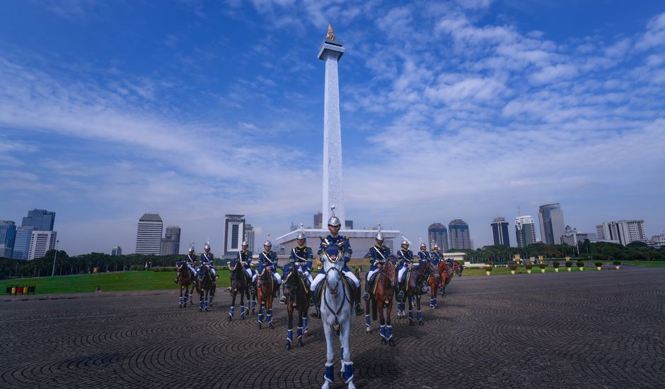 Horse guards parade in front of Jakarta's iconic National Monument.
