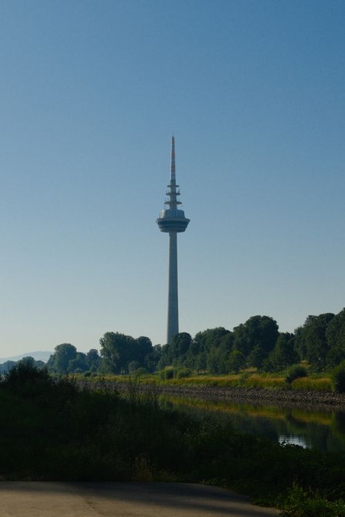 Free A towering structure stands against a clear blue sky beside a lush riverside landscape. Stock Photo