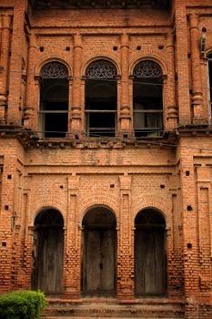 Vintage brick facade with arched windows and doors, showcasing historic architecture.