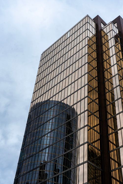 Free A striking modern skyscraper in Vancouver with reflective glass panels against a cloudy sky. Stock Photo