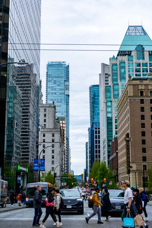 Free Vibrant downtown Vancouver with people crossing, skyscrapers, and city life. Ideal for urban, travel, and architecture themes. Stock Photo
