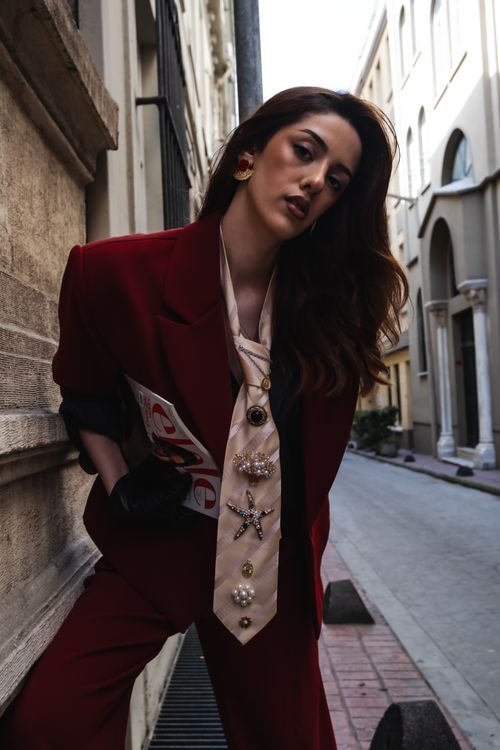 Free Woman in a bold red suit poses stylishly on a city street. Stock Photo
