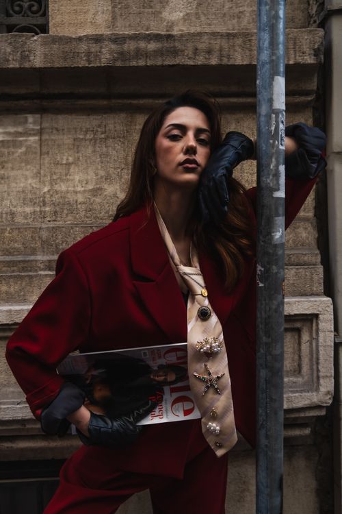 Free Stylish woman in red suit with magazine outdoors, moody fashion. Stock Photo