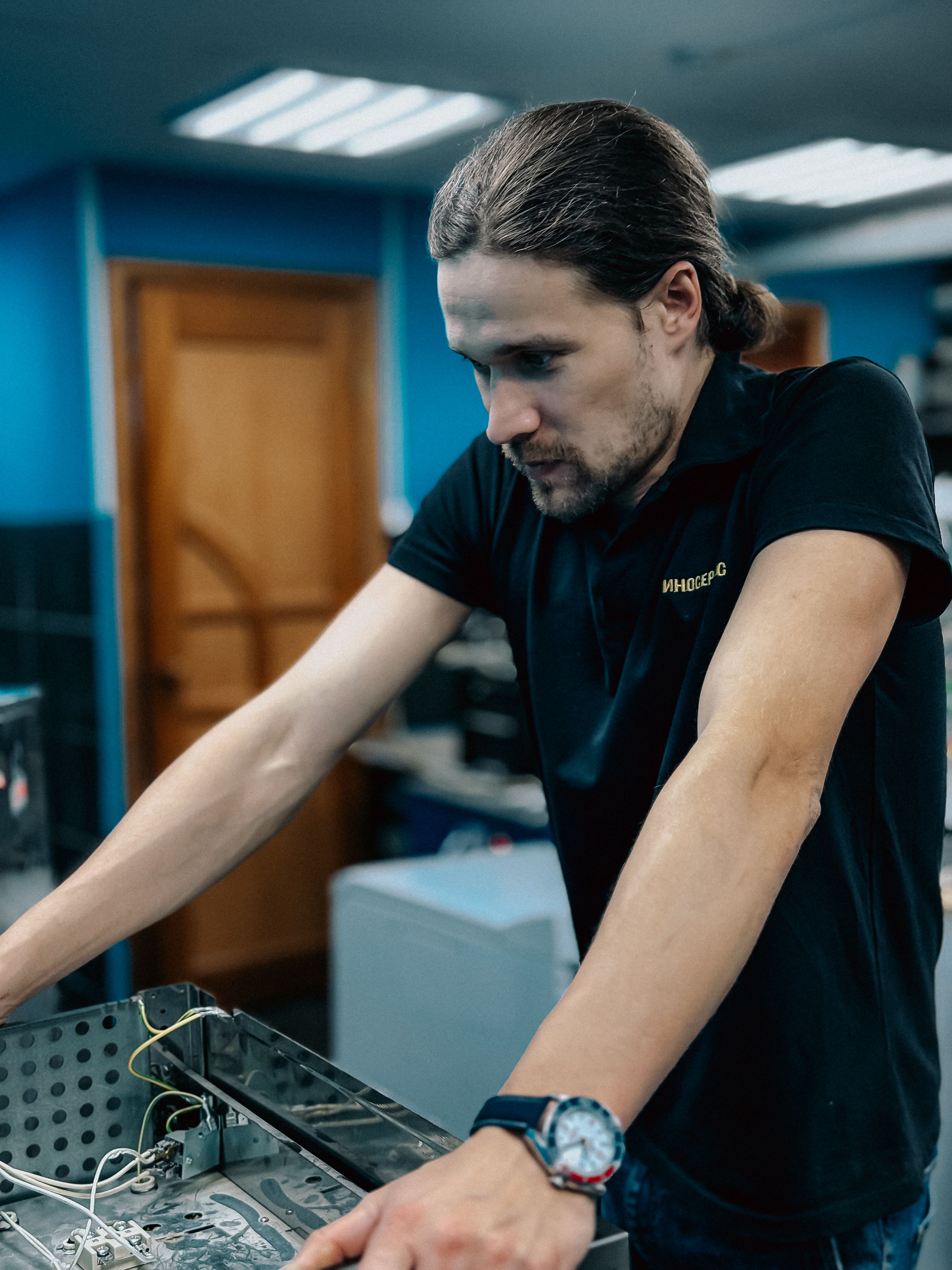 A technician intensely works on assembling computer hardware in a tech workspace.