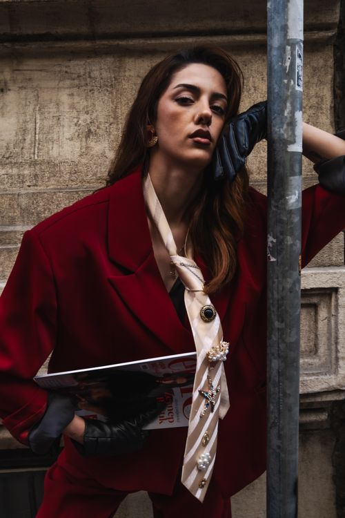 Free Stylish woman in red suit leans on pole, showcasing urban fashion. Stock Photo