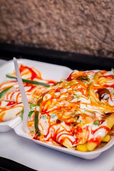 Delicious tray of loaded fries with creamy sauce and chili, perfect street food option.