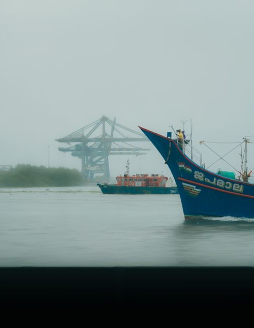 Free Fishing boats navigate the waters near Kochi Port, Kerala, under a foggy sky, capturing serene maritime life. Stock Photo