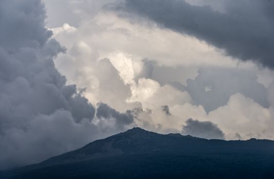 Captivating view of dramatic clouds hovering over a mountain peak, showcasing nature's power.