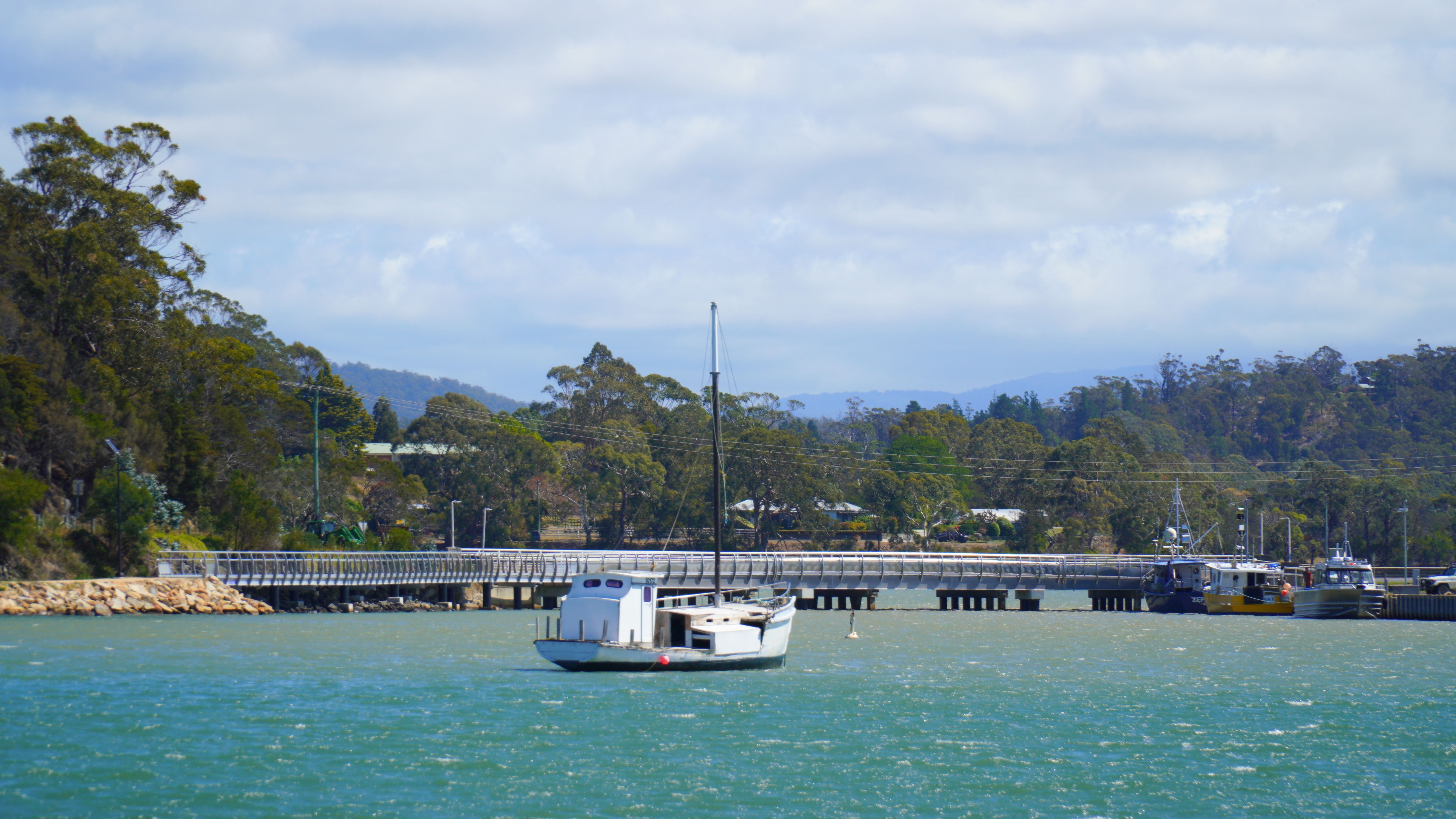 A tranquil view of a yacht on the water near a bridge in St Helens, Tasmania.