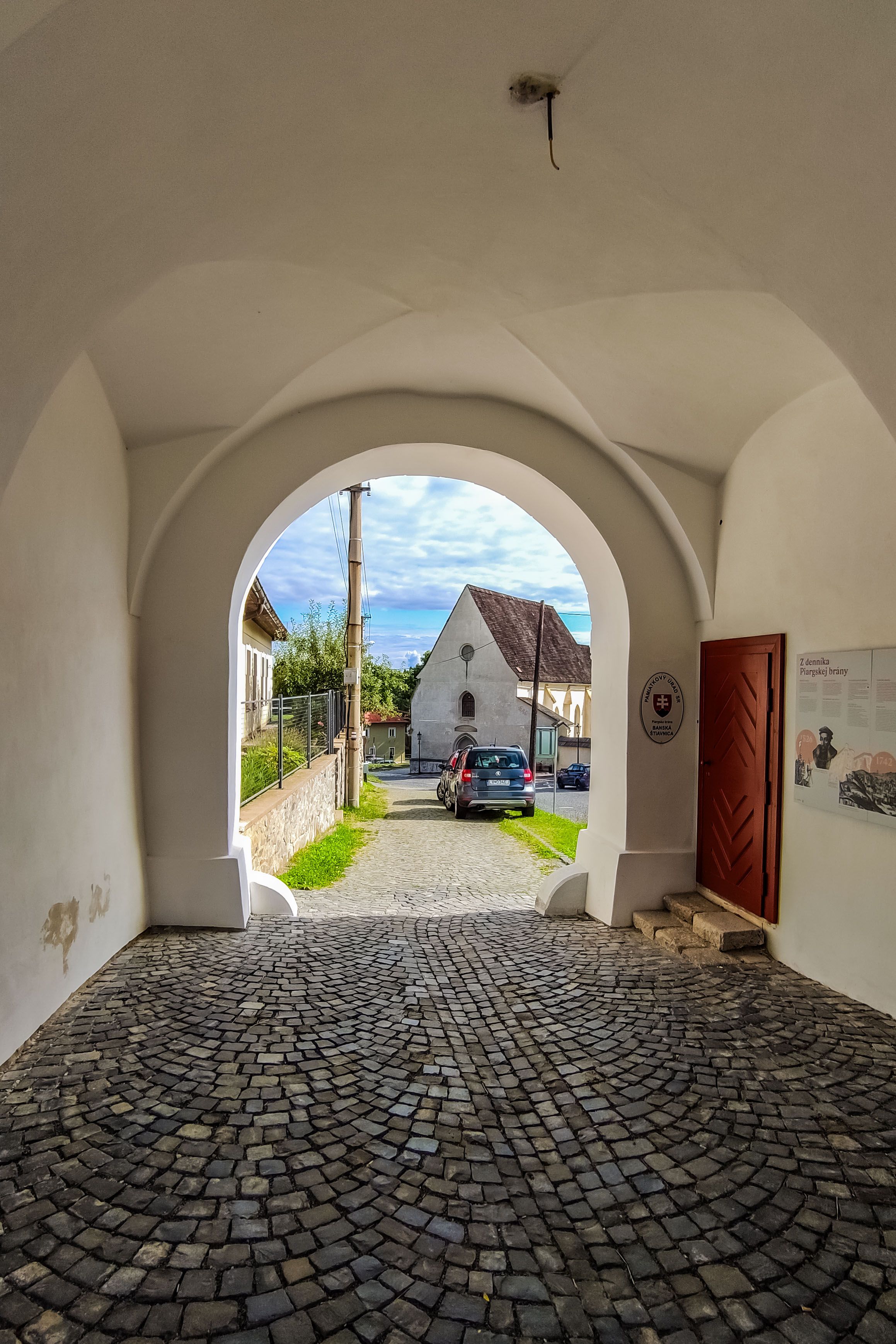 A view through an archway revealing a cobblestone street and picturesque village.