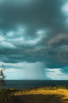 Captivating storm clouds and rain over the ocean, with lush greenery in the foreground, in Quảng Trị.