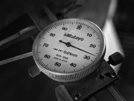 Detailed black and white image of a Mitutoyo dial indicator measuring tool, showcasing precision engineering.