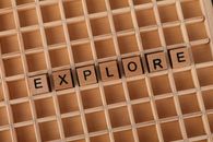 Wooden grid with letter blocks spelling 'EXPLORE', symbolizing discovery.