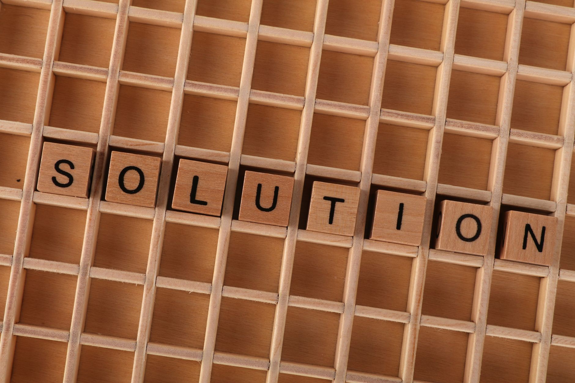 Wooden blocks spelling 'solution' in a grid, symbolizing problem-solving.