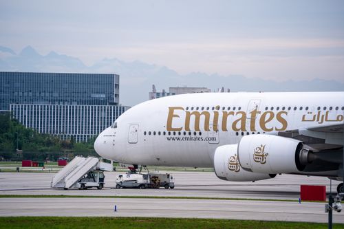 Free A close-up shot of an Emirates Airbus A380 parked at an airport terminal with ground support vehicles. Stock Photo