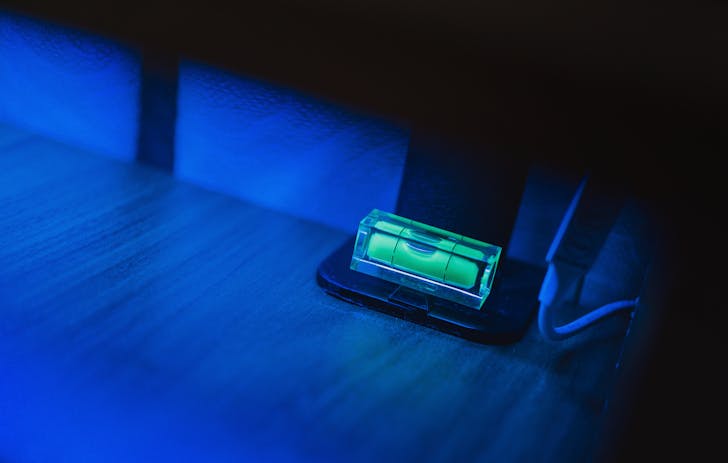 Small illuminating green neon bubble level placed on monitor stand in dark room