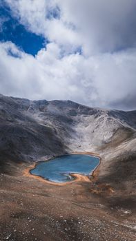 A serene mountain lake surrounded by rocky terrain under a sky filled with dramatic clouds.