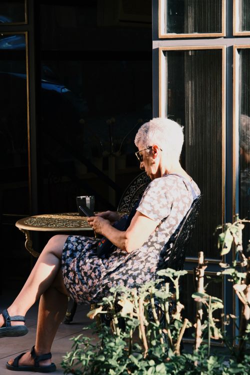 Free Senior woman with short hair enjoying a sunny day at an outdoor cafe. Stock Photo