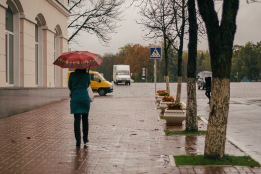 A person with an umbrella walks on a rainy street in Chernihiv, capturing the essence of daily life.