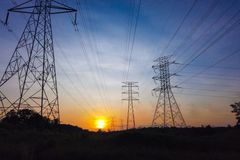 Silhouetted power lines and towers against a striking sunset sky, illustrating energy supply themes.