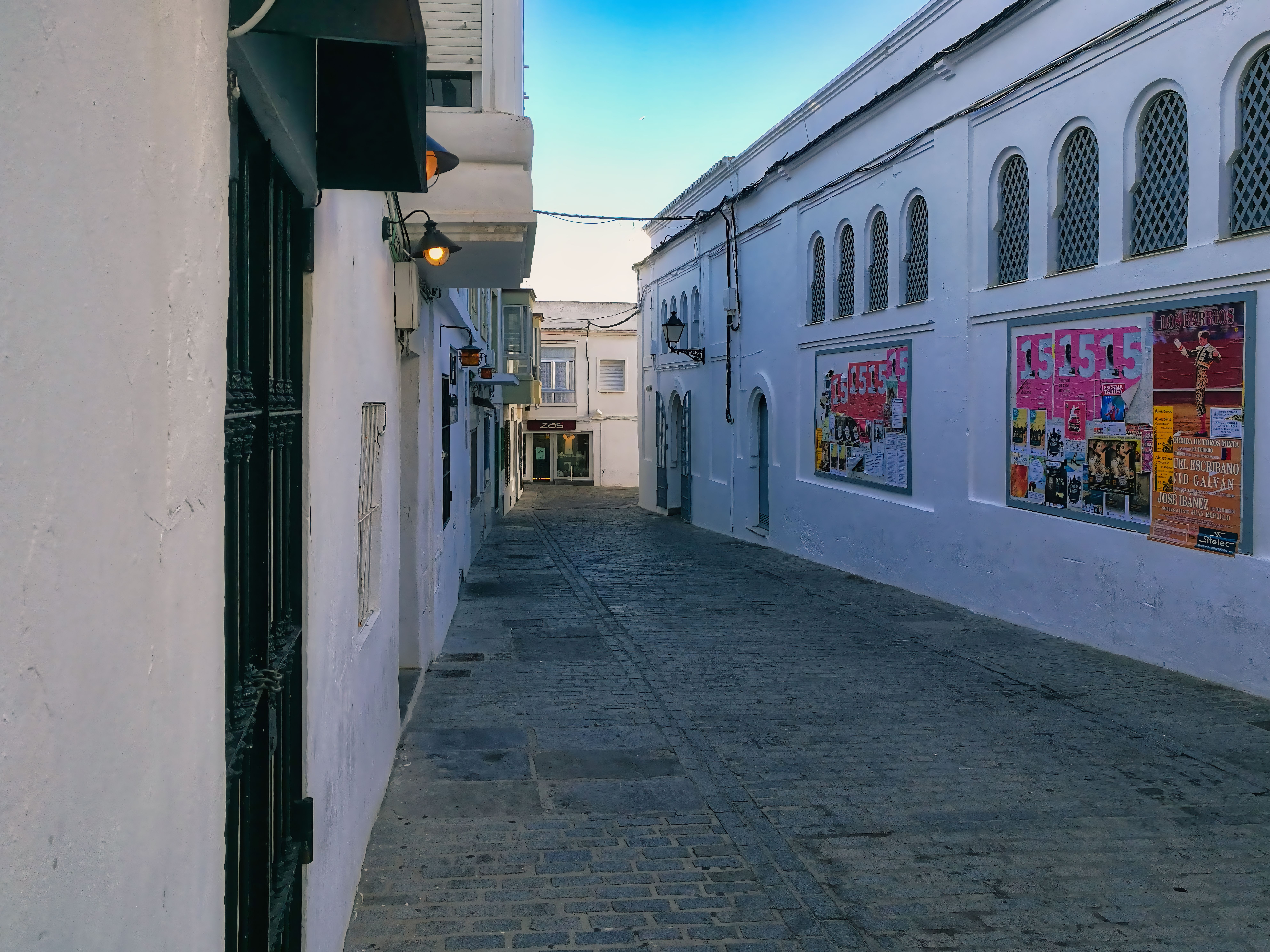 Explore the quiet charm of a narrow alleyway in Tarifa, Andalusia, adorned with vibrant posters.