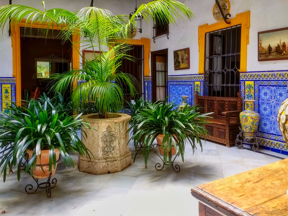 Curte interioară din Sevilla, cu azulejos pe pereți și plante în ghivece