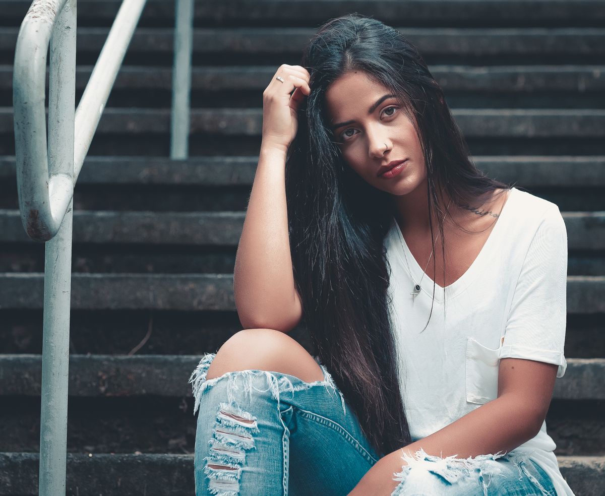 Woman wearing a white tee with jeans, sitting on stairs