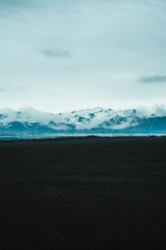 Captivating view of Iceland's glacial mountains enveloped in clouds on a moody day.