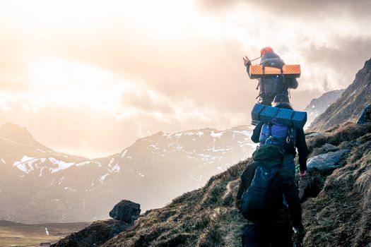 A group of hikers trekking up a mountainous trail in Nordland, Norway at sunset.