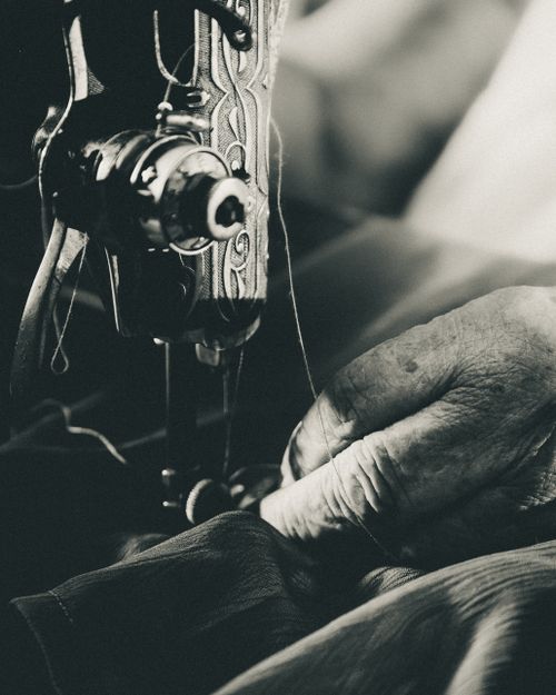 Free Close-up of an elderly person's hands using a vintage sewing machine in black and white. Stock Photo