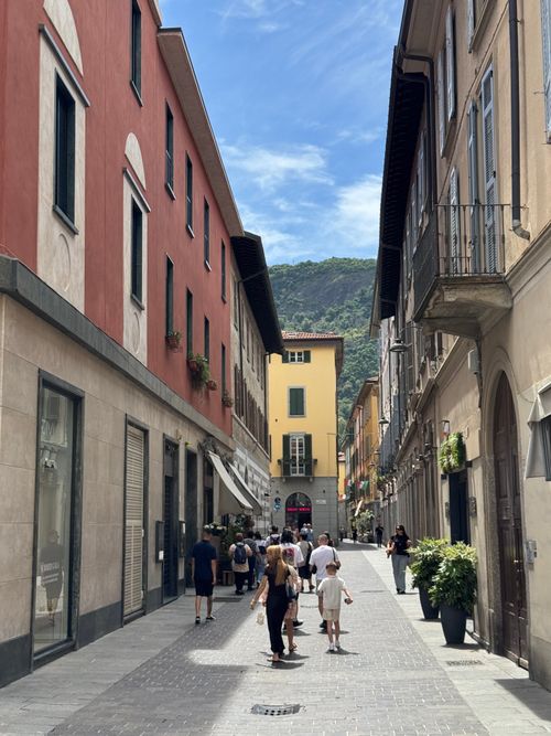Free A bustling street in Lecco, Italy, with people strolling under a clear summer sky. Stock Photo