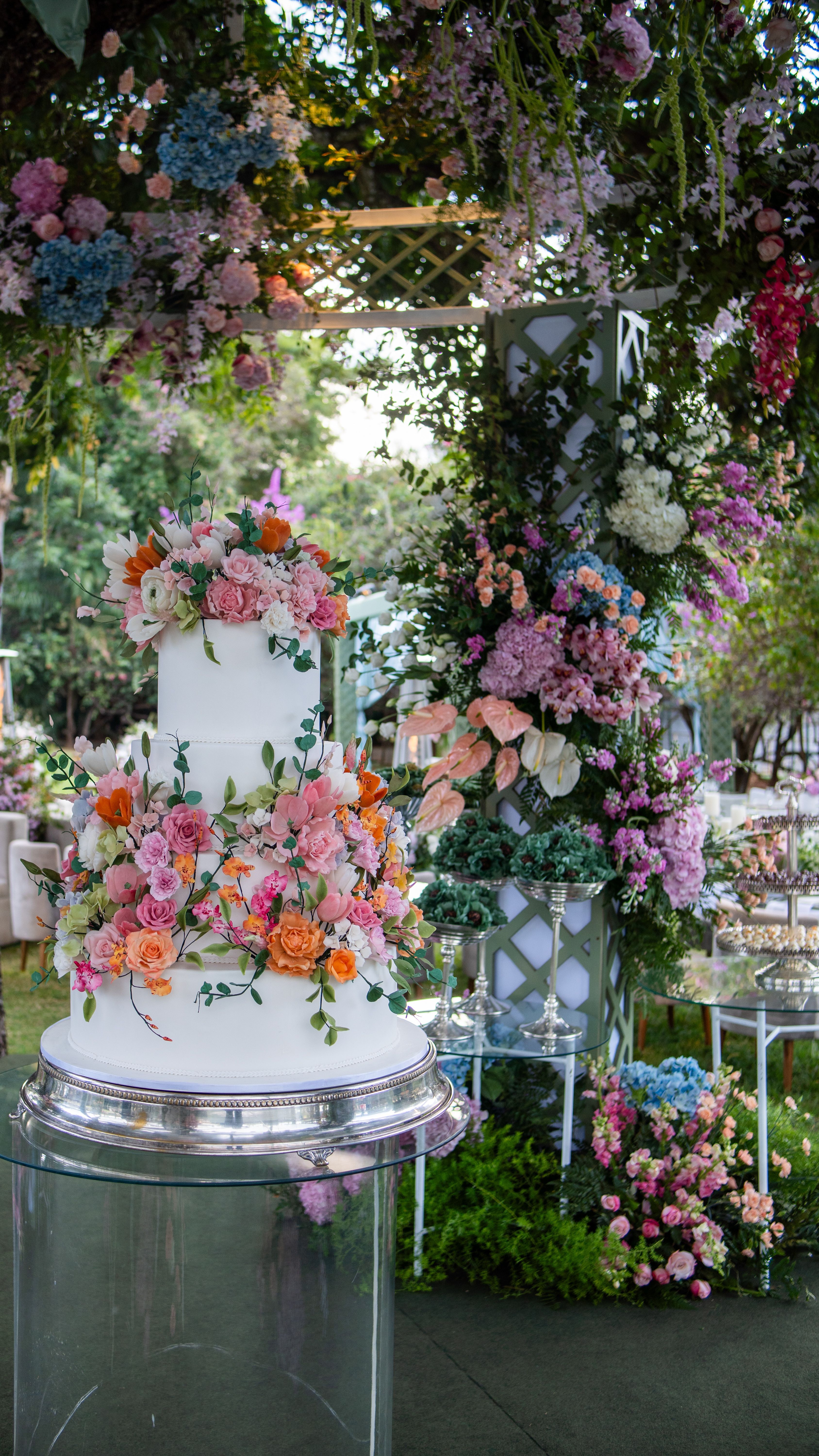 A decorative wedding cake with vibrant floral arrangements set in an outdoor garden setting.