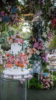 A decorative wedding cake with vibrant floral arrangements set in an outdoor garden setting.