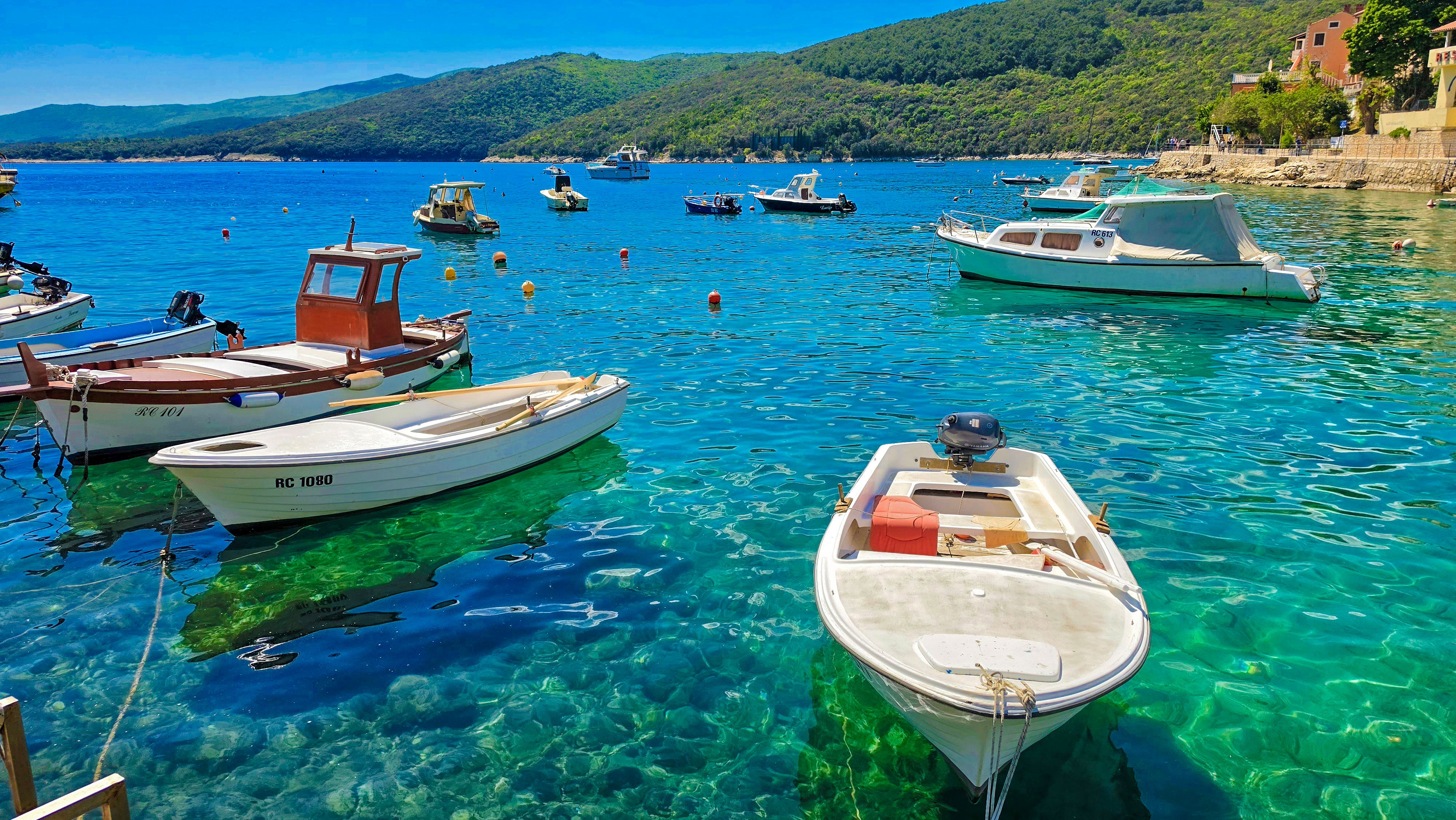Idyllic view of boats floating in clear turquoise waters of Kvarner Bay, Croatia under a bright summer sky.