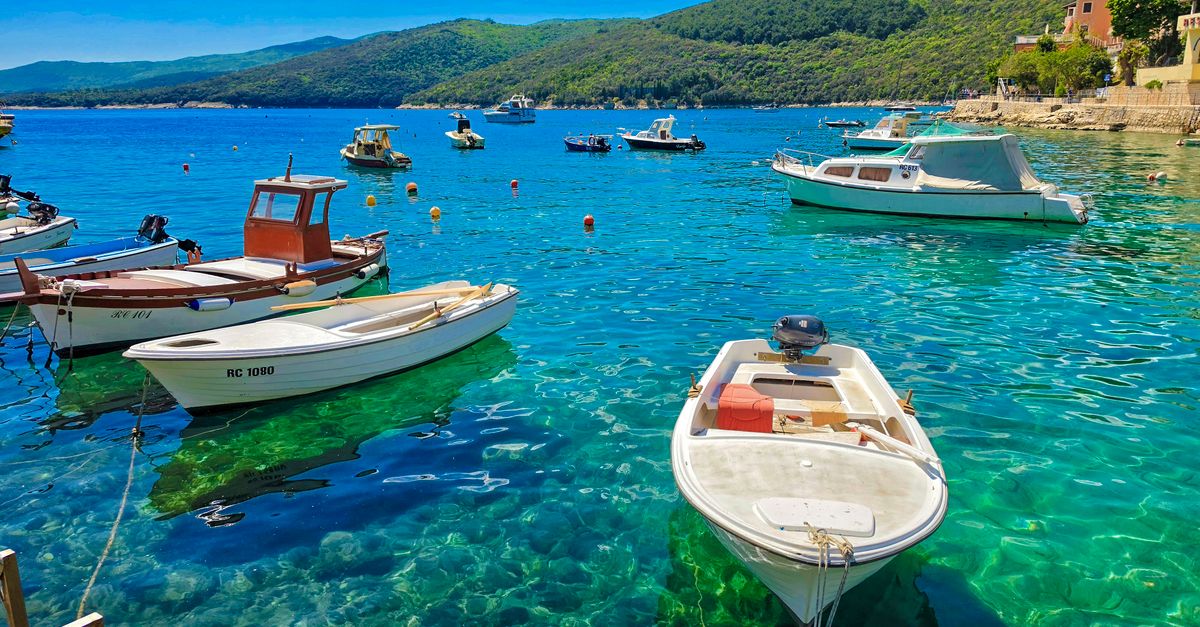 Idyllic view of boats floating in clear turquoise waters of Kvarner Bay, Croatia under a bright summer sky.