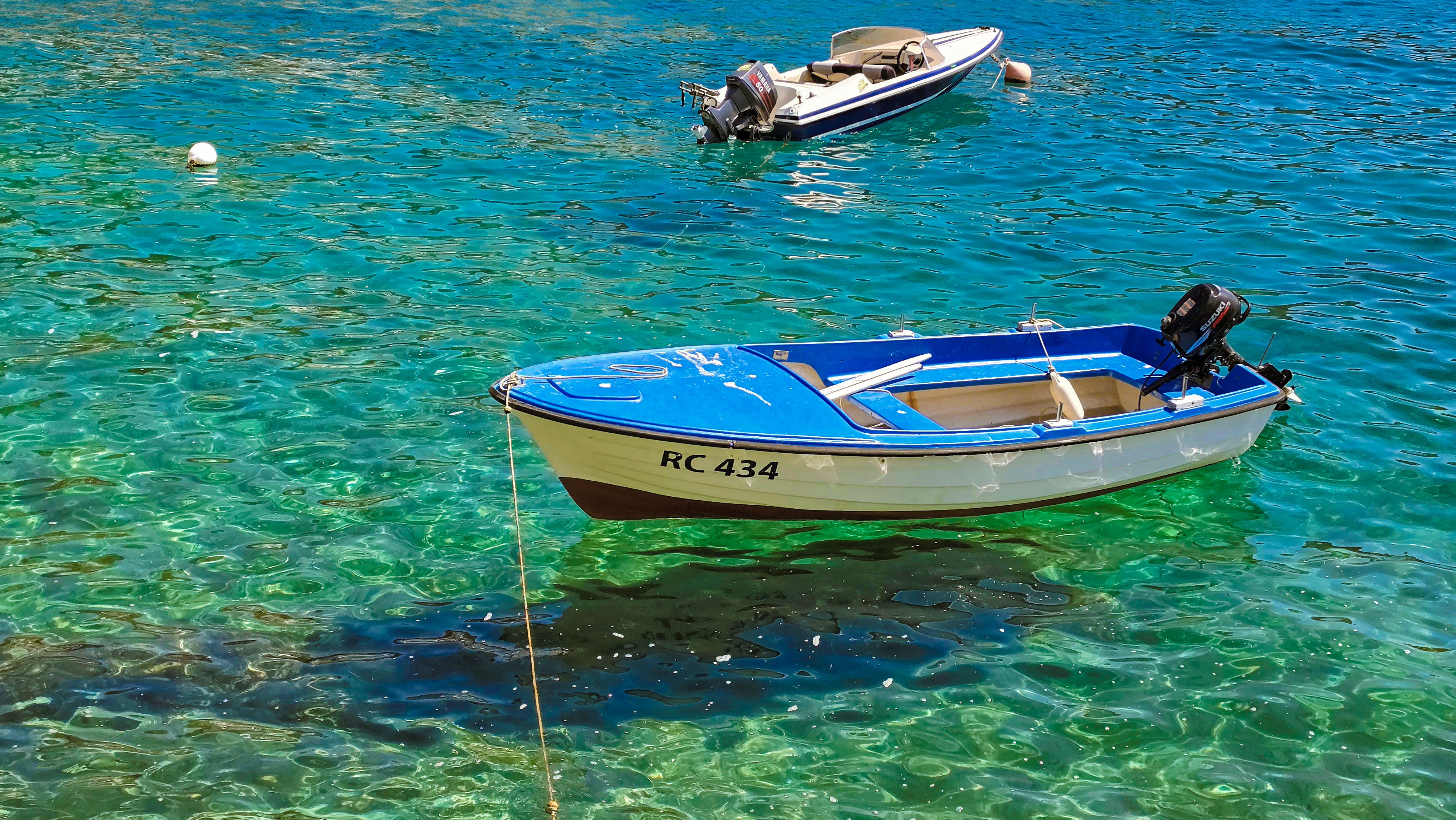 Small blue and white boats floating on vibrant, clear water, perfect for travel and leisure imagery.